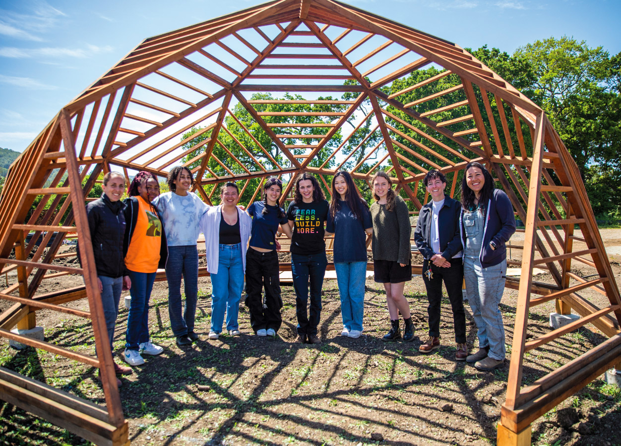 10 young women pose inside an open wooden dome